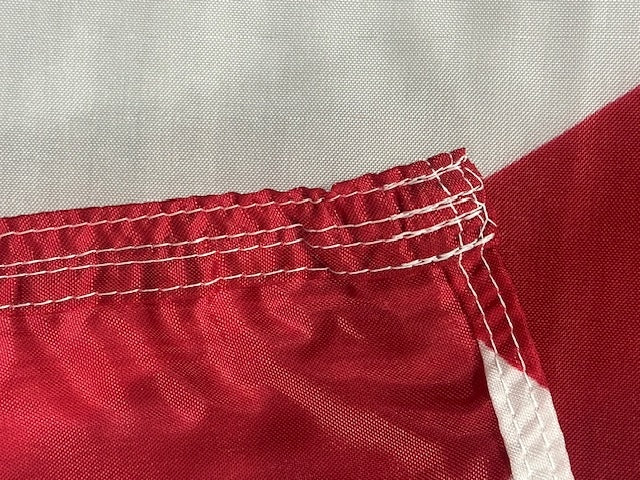 Close-up of red fabric with white stitching on a Alabama Nylon Flag