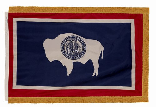 A indoor Wyoming flag with gold fringe on a white background.