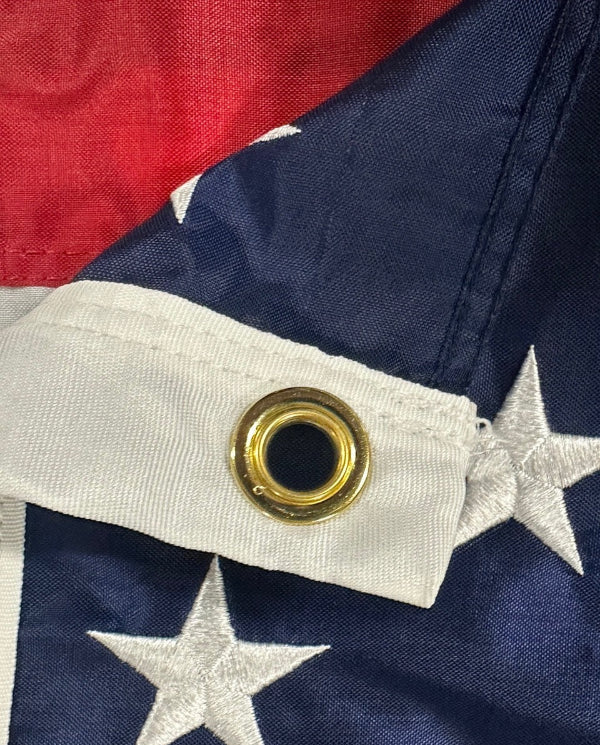 Close-up of a flag with a gold grommet and red, white, and blue colors.